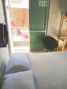 a bed in a room with a window and a chair at Loft pé na areia in Florianópolis
