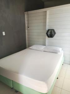 a large white bed in a room with a wall at Loft pé na areia in Florianópolis