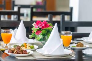 Hotel Bob's N Barley في دارامشالا: طاولة مع أطباق من الطعام وكؤوس من عصير البرتقال