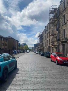 two cars parked on a brick street with buildings at Excellent one bedroom apartment Dundee in Dundee