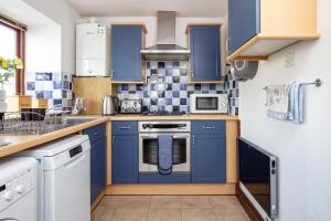 a small kitchen with blue cabinets and appliances at Ferienhaus für 4 Personen ca 53 qm in Saint Columb Major, England Westküste von England in Saint Columb Major