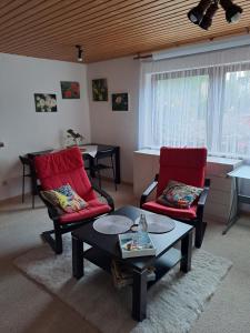 Sala de estar con 2 sillas rojas y mesa de centro en Ferien- und Business Wohnung, en Mönsheim