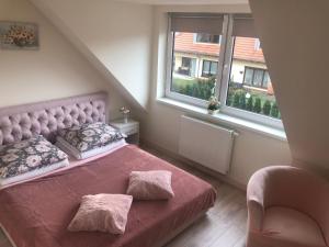 1 dormitorio con cama rosa y ventana en Słoneczne Apartamenty Polanica-Zdrój en Polanica-Zdrój