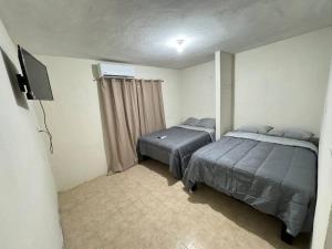 a bedroom with two beds and a flat screen tv at Cómoda Casa en Tampico a 15 min de Playa Miramar in Tampico
