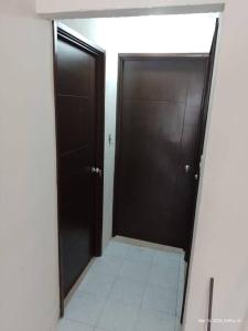 korytarz z dwoma czarnymi drzwiami i podłogą wyłożoną kafelkami w obiekcie Cómoda Casa en Tampico a 15 min de Playa Miramar w mieście Tampico