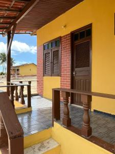 Casa amarilla con puerta de madera y banco en Pargos Club de Salinas, en Salinópolis