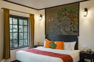 um quarto com uma cama grande com almofadas laranja e verde em The Hive, Wayanad em Wayanad