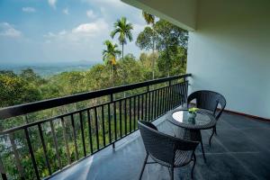 a balcony with a table and chairs and a view at The Hive, Wayanad in Wayanad