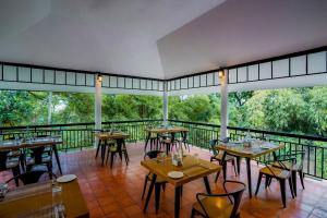 een restaurant met tafels en stoelen op een balkon bij The Hive, Wayanad in Wayanad