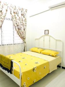 een wit bed met gele lakens en gele kussens bij Lovely Jannah Cottage Kulim in Kulim