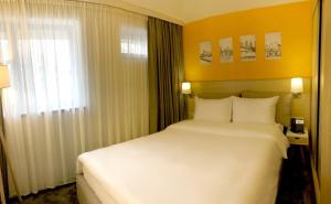 Un dormitorio con una gran cama blanca y una ventana en Hotel In City, en Ereván