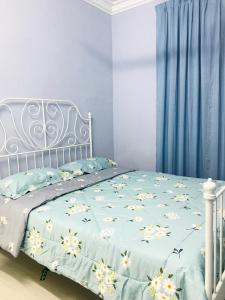 een bed met een blauwe deken met bloemen erop bij Lovely Jannah Cottage Kulim in Kulim