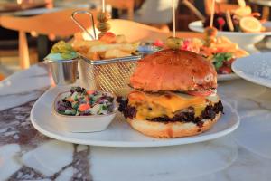 a plate of food with a cheeseburger and a salad at west coast boutique hotel in Bodrum City