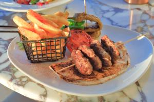 a plate of food with meat and a basket of french fries at west coast boutique hotel in Bodrum City