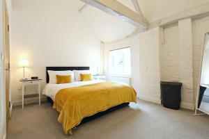 um quarto com uma cama com um cobertor amarelo em Oakdale at Weavers Yard No2 em Farnham