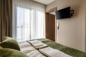 ein Hotelzimmer mit einem Bett und einem Flachbild-TV in der Unterkunft Dom Wczasowy Zew Morza in Jastrzębia Góra