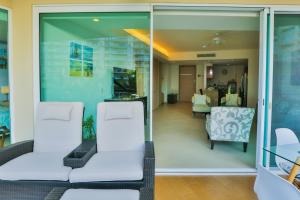 a living room with glass doors and white chairs at Departamento a pie de playa in Nuevo Vallarta