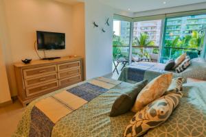 a bedroom with two beds and a television and a balcony at Departamento a pie de playa in Nuevo Vallarta