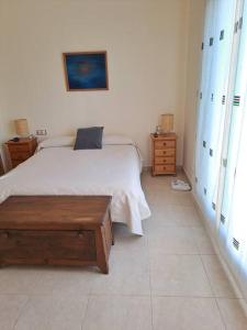 una camera bianca con letto e panca in legno di Casa en Sant Jordi a Sant Jordi