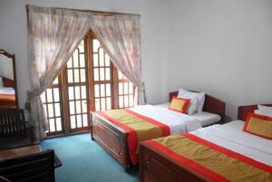 Un dormitorio con dos camas y una gran ventana. en Birds Peak Hotel Nuwaraeliya, en Nuwara Eliya