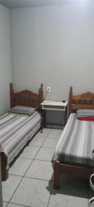 a room with two beds and a desk in it at Pousada Econômica in Uberlândia
