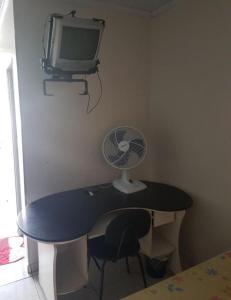 a desk with a fan and a television on a wall at Pousada Econômica in Uberlândia