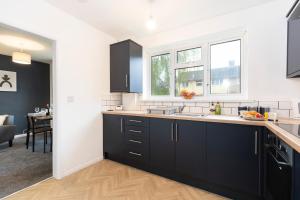 a kitchen with black cabinets and a living room at Jameson Lodge in Hartlepool