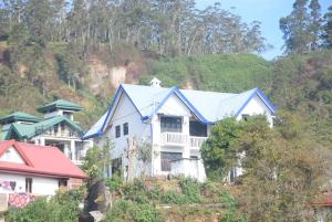 una casa blanca con techo azul en una colina en Birds Peak Hotel Nuwaraeliya, en Nuwara Eliya
