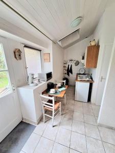 een kleine keuken met een tafel en een tafel en stoelen bij Studio 11 - Longère Bruyères - Morbihan in Sulniac