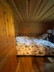ein Schlafzimmer mit einem Bett in einem Holzzimmer in der Unterkunft Mökki luonnon keskellä. in Tervola