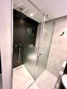 y baño con ducha y puerta de cristal. en Alexandrion Appartements Down Town, en Sarti