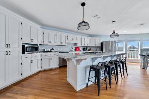 eine Küche mit weißen Schränken und eine große Insel mit Barhockern in der Unterkunft Beach Energy in Gulf Shores