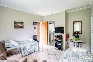 a living room with two beds and a tv at LeoZet Self catering apartment in Pretoria