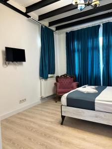 Schlafzimmer mit einem Bett, einem TV und einem Stuhl in der Unterkunft VOLGAİSTANBUL in Istanbul