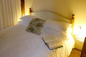 una cama con una almohada y un libro sobre ella en Ferienhaus für 2 Personen ca 50 qm in Stokeinteignhead, England Südküste von England en Stokeinteignhead