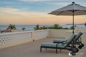 a chair and an umbrella on a balcony with the ocean at Luxe Oceanview Villa with Pool Hot Tub BBQ and Fire Pit in San José del Cabo +36 photos