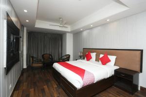 1 dormitorio con 1 cama grande con almohadas rojas en Super OYO The Avenue Residency Near Leisure Valley Park en Gurgaon