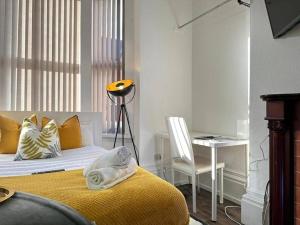 ein Schlafzimmer mit einem Bett mit einer gelben Decke und einem Stuhl in der Unterkunft Tranquil Haven Studio Escape in Vibrant Birmingham in Birmingham