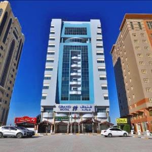 Grand PJ Hotel - Free Parking في رأس الخيمة: مبنى كبير فيه سيارات تقف امامه