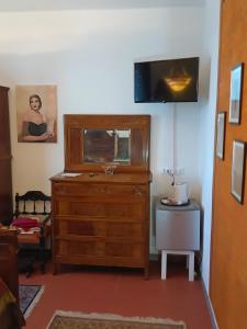 a room with a dresser and a tv on a wall at La Maison Rouge in Crespellano