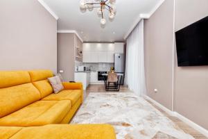 a living room with a yellow couch and a kitchen at 2-х комнатная возле ЭКСПО in Astana