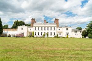 una gran casa blanca con un gran campo de césped en Haughton Hall en Telford