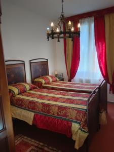 two beds in a bedroom with red curtains at La Maison Rouge in Crespellano