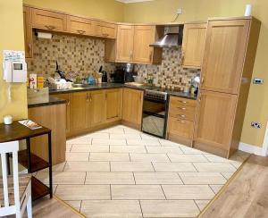 a kitchen with wooden cabinets and a tile floor at Simple Compact House ! in Wythenshawe