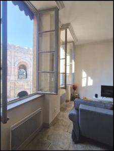 een woonkamer met een bank en een groot raam bij L'appartement des Arènes - Nîmes in Nîmes