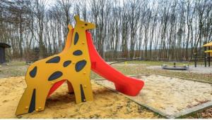 una giraffa di plastica su uno scivolo in un parco giochi di Schönes Ferienhaus am Twistesee - b62252 a Bad Arolsen