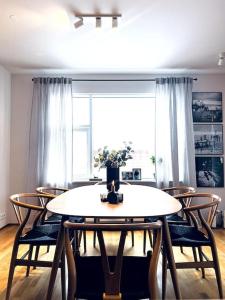 a dining room table with chairs and a window at Lovely 2 bedroom apartment with a large own patio in Garðabær