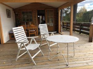 two white chairs and a table on a deck at Ferienhaus in Västerrå mit Garten und Terrasse 