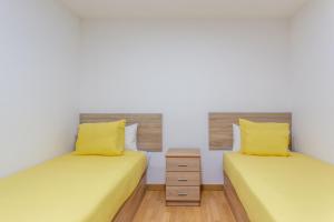 two twin beds in a room with yellow pillows at Apartamento 3 habs Madrid in Madrid