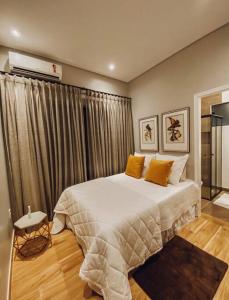una camera da letto con un grande letto bianco con cuscini gialli di Recanto do Sossego Refúgio de férias em Minas a Piranguçu